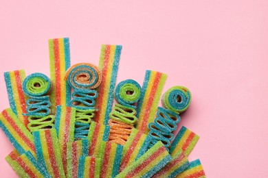 Photo of Tasty rainbow sour belts on pink background, top view