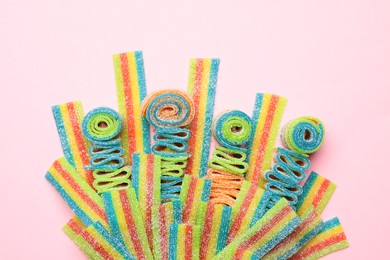 Photo of Tasty rainbow sour belts on pink background, top view