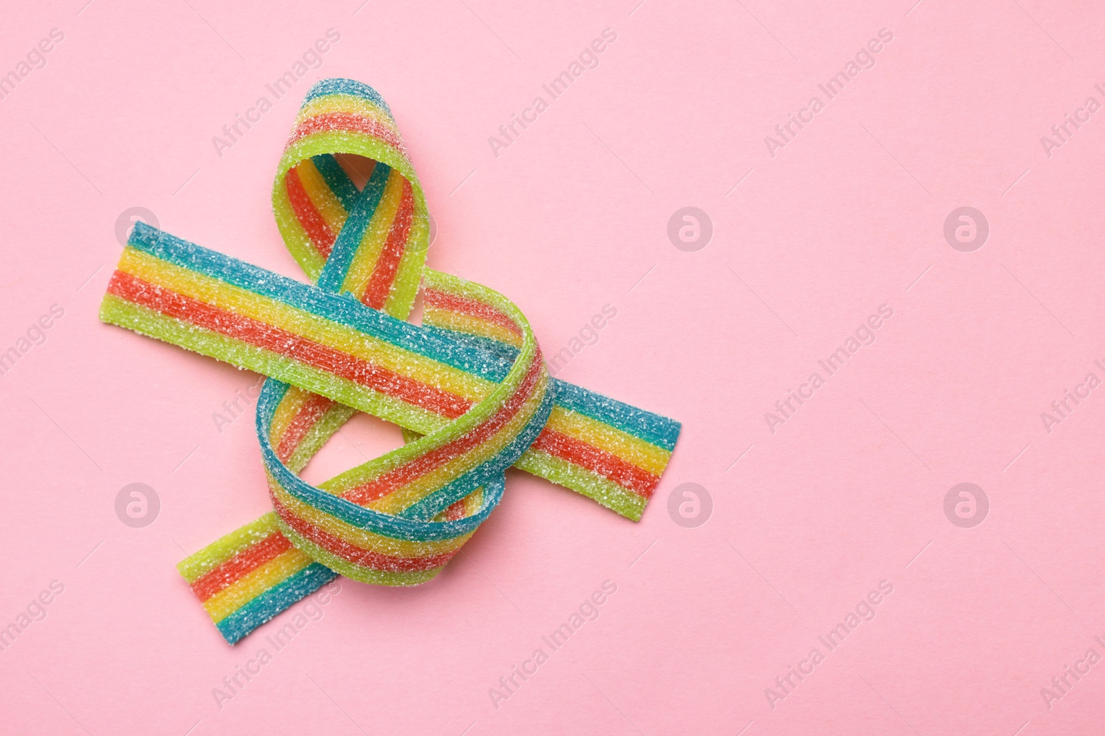 Photo of Tasty rainbow sour belts on pink background, top view. Space for text