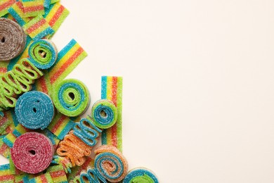 Photo of Different tasty sour belts on beige background, top view. Space for text