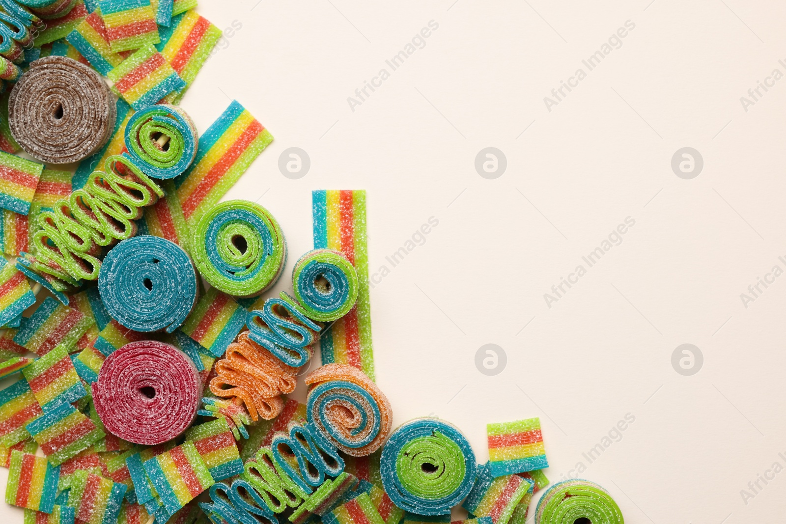 Photo of Different tasty sour belts on beige background, top view. Space for text