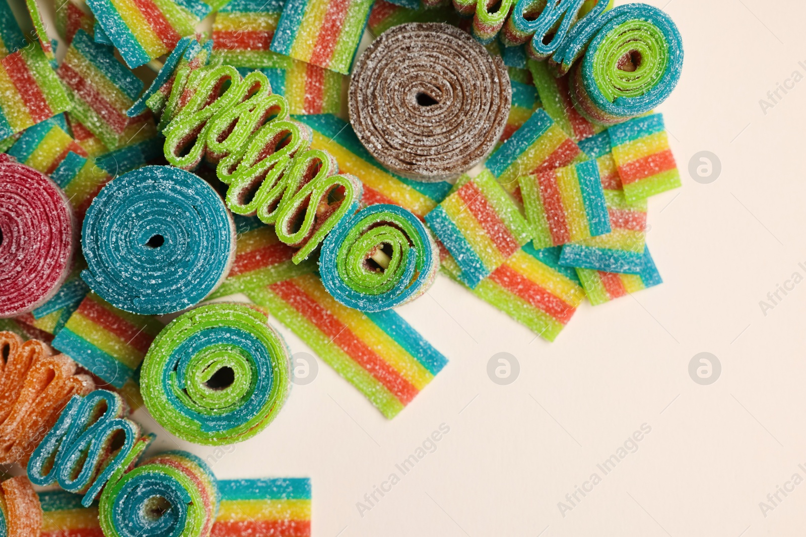 Photo of Different tasty sour belts on beige background, top view