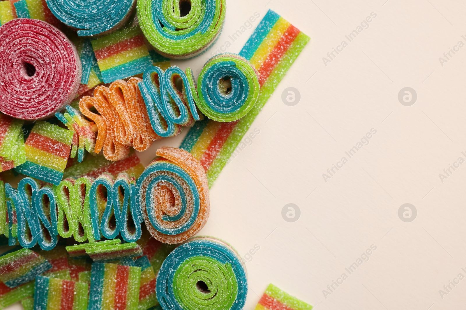 Photo of Different tasty sour belts on beige background, top view. Space for text