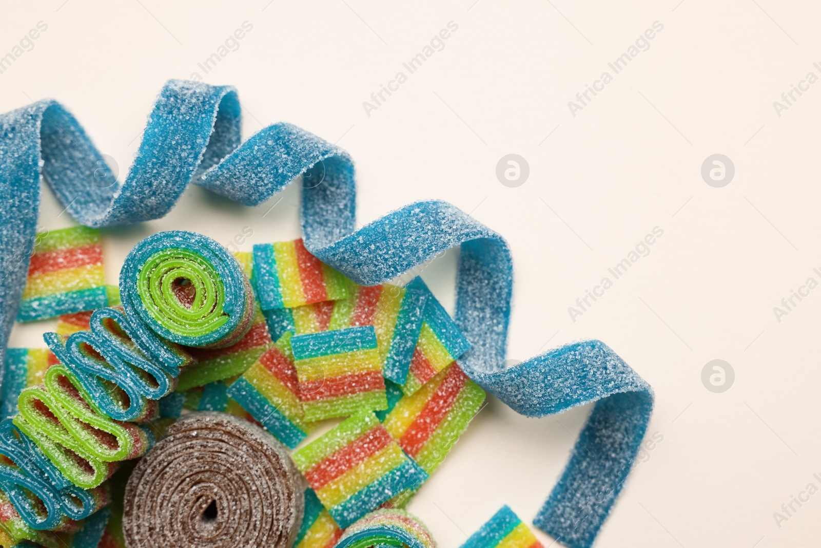 Photo of Different tasty sour belts on beige background, top view