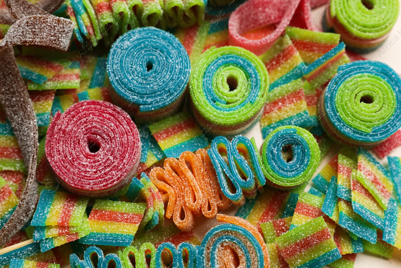 Photo of Different tasty sour belts as background, above view