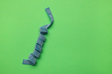 Photo of Tasty blue sour belt on green background, top view. Space for text