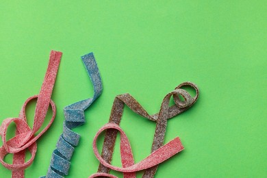 Photo of Different tasty sour belts on green background, flat lay