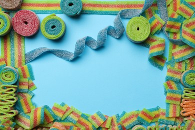 Photo of Frame of different tasty sour belts on light blue background, flat lay. Space for text