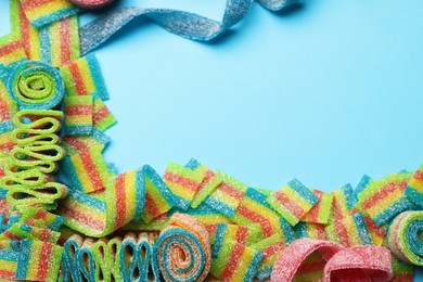 Photo of Different tasty sour belts on light blue background, flat lay. Space for text