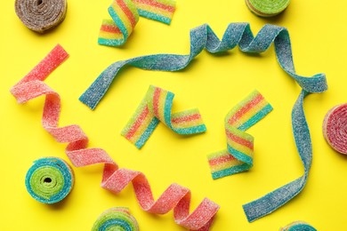 Photo of Different tasty sour belts on yellow background, flat lay