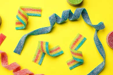 Photo of Different tasty sour belts on yellow background, flat lay