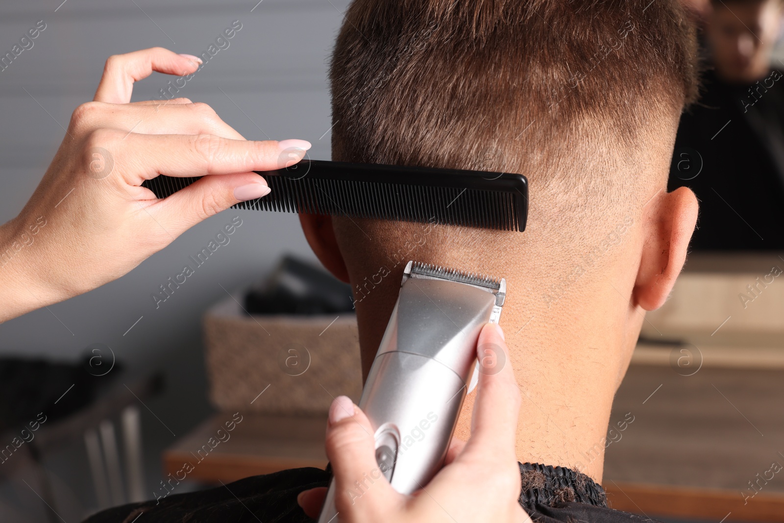 Photo of Professional barber making stylish haircut in salon, closeup