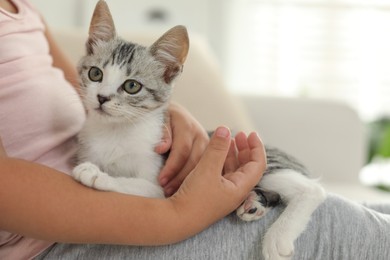 Photo of Little girl with cute kitten at home, closeup