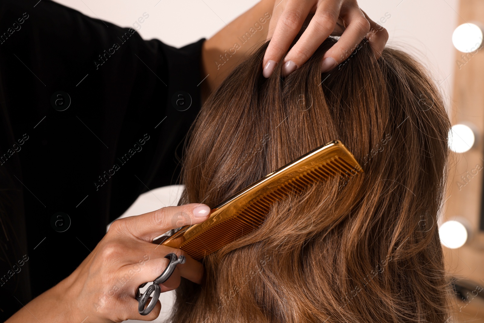 Photo of Hairdresser combing woman's hair in salon, closeup