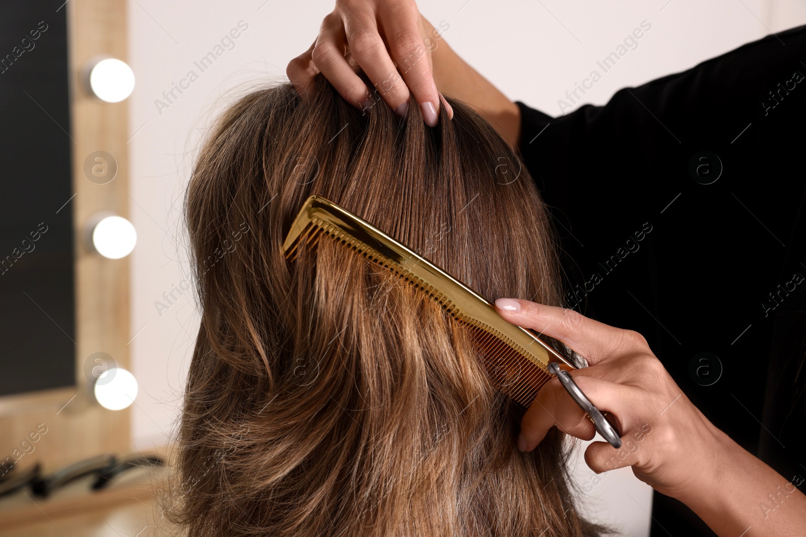 Photo of Hairdresser combing woman's hair in salon, closeup