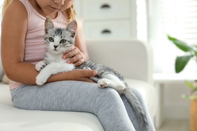 Photo of Little girl with cute kitten at home, closeup