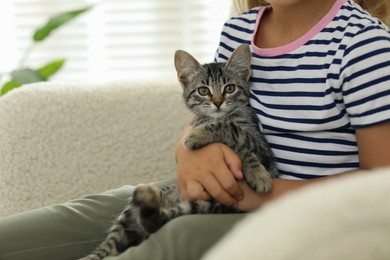 Photo of Little girl with cute kitten at home, closeup