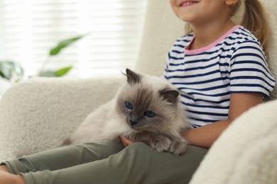 Photo of Little girl with cute kitten at home, closeup