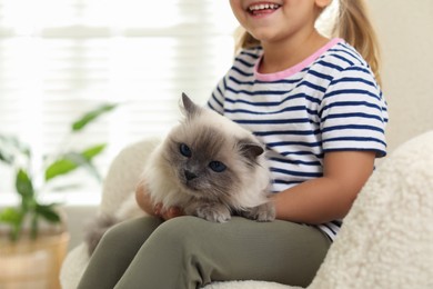 Photo of Little girl with cute kitten at home, closeup