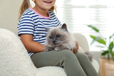 Photo of Little girl with cute kitten at home, closeup