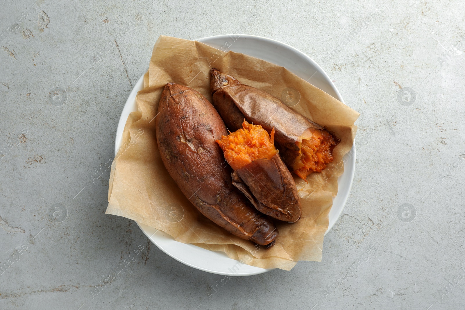 Photo of Tasty cooked sweet potatoes served on light grey table, top view