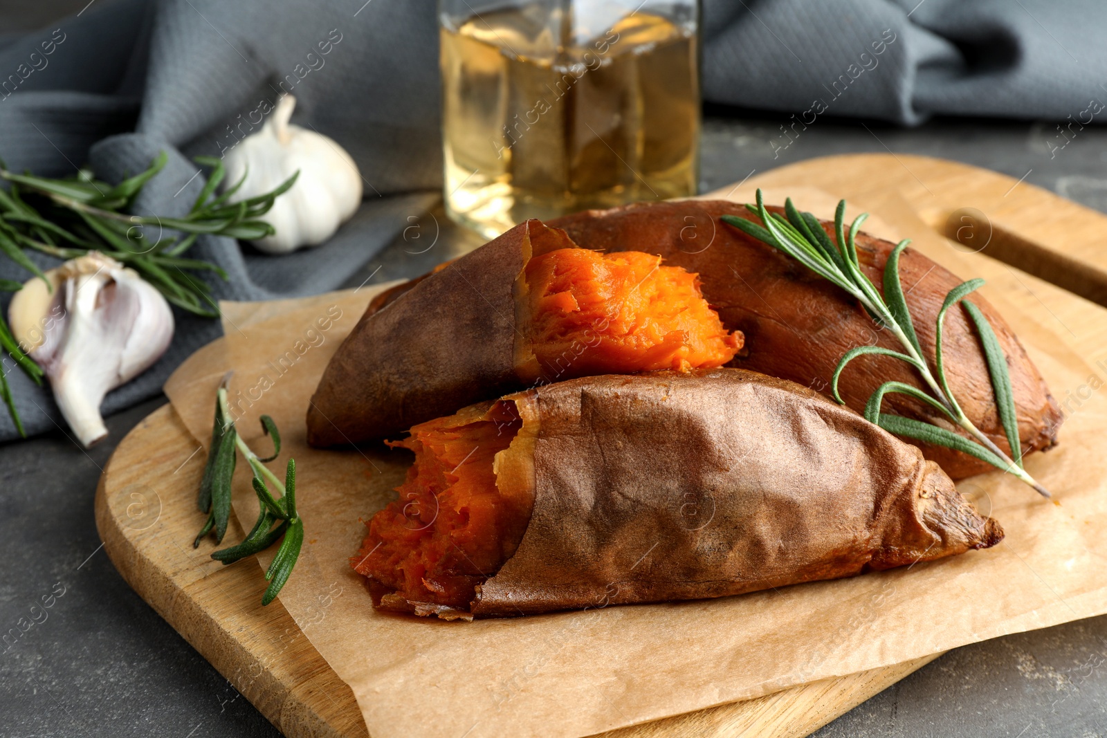 Photo of Tasty cooked sweet potatoes served with rosemary on grey table, closeup