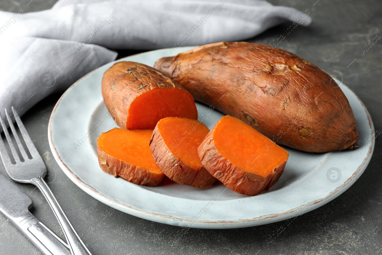 Photo of Tasty cooked sweet potatoes served on grey table