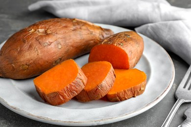 Photo of Tasty cooked sweet potatoes served on grey table, closeup