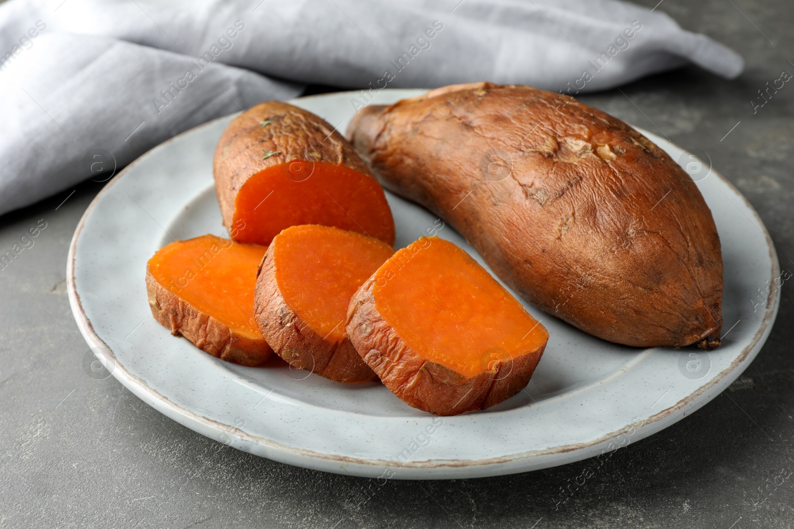 Photo of Tasty cooked sweet potatoes served on grey table