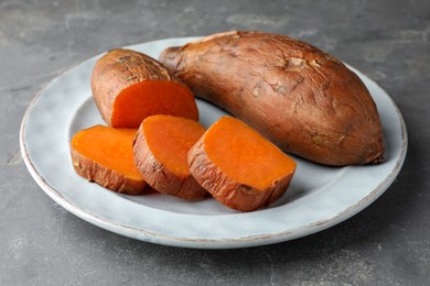 Photo of Tasty cooked sweet potatoes served on grey table