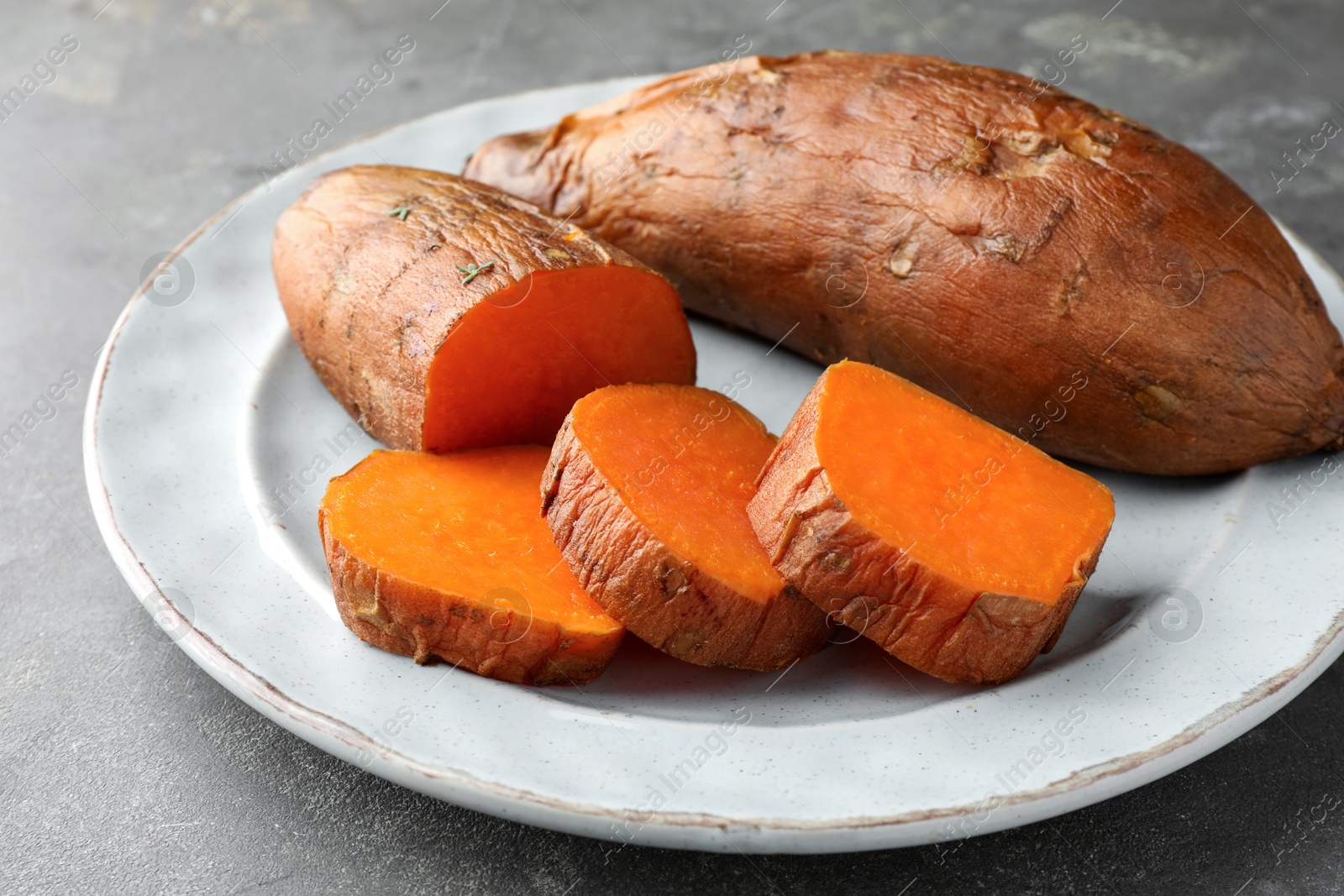 Photo of Tasty cooked sweet potatoes served on grey table, closeup