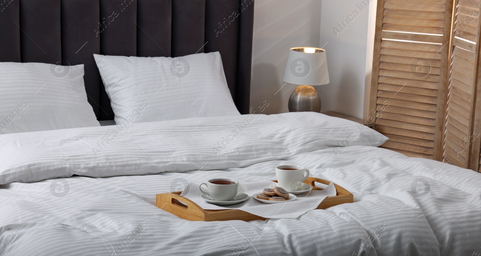 Photo of Breakfast tray on bed with beautiful linens indoors