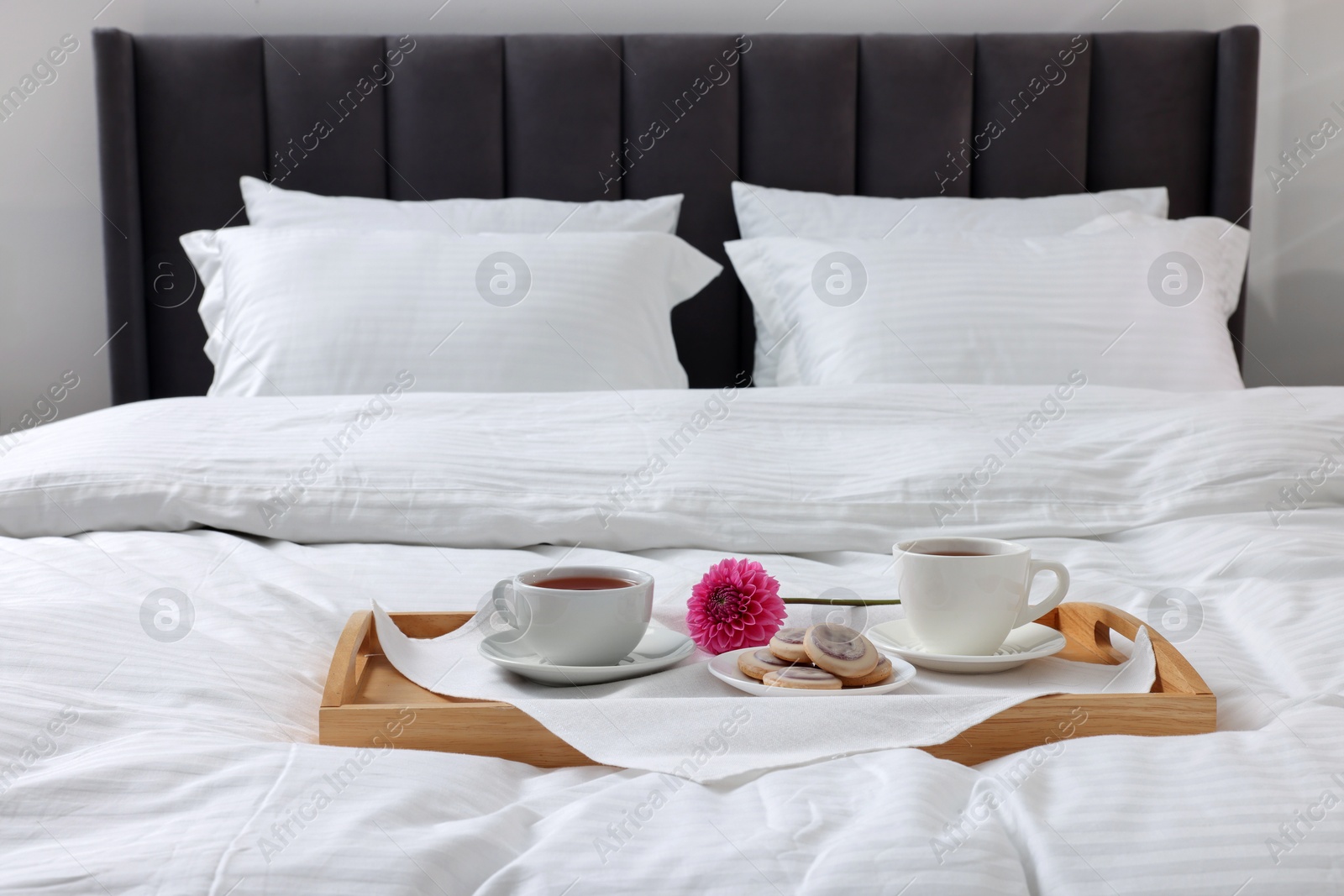 Photo of Breakfast tray on bed with beautiful linens indoors