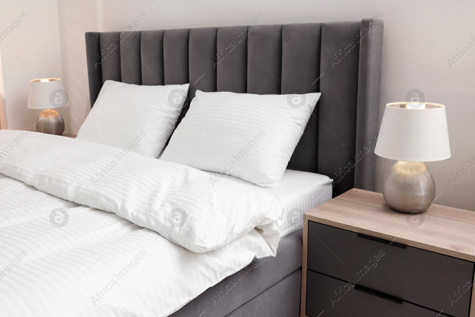 Photo of Bed with clean linens and pillows indoors