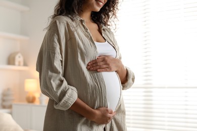 Photo of Pregnant woman near window at home, closeup