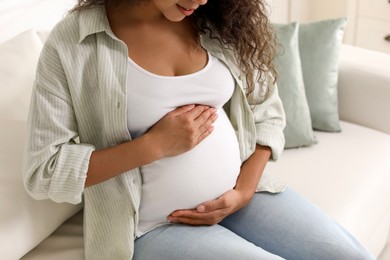 Photo of Pregnant woman on sofa at home, closeup