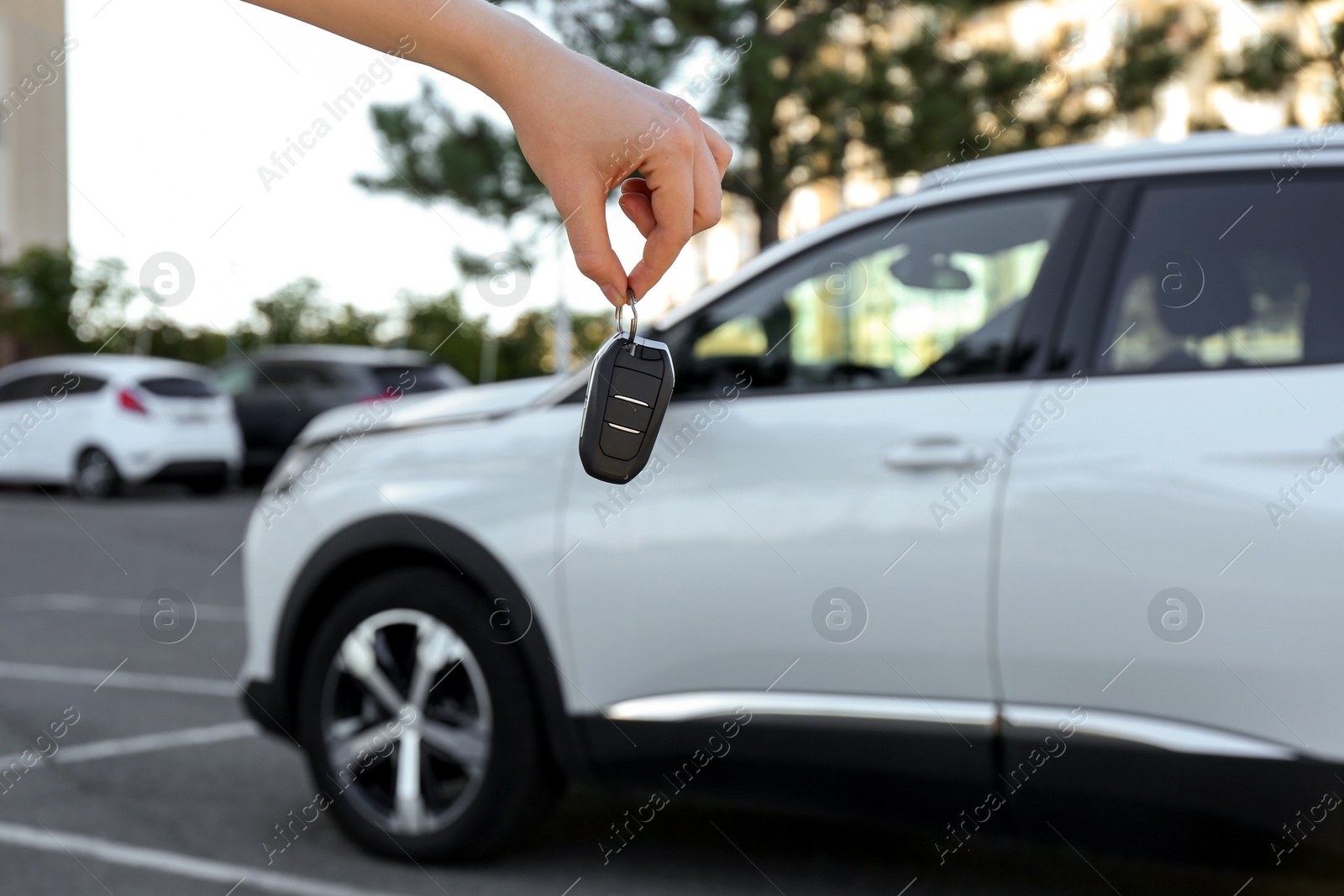 Photo of Woman holding key near car outdoors, closeup