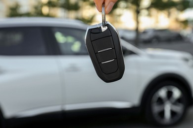 Photo of Woman holding key near car outdoors, closeup