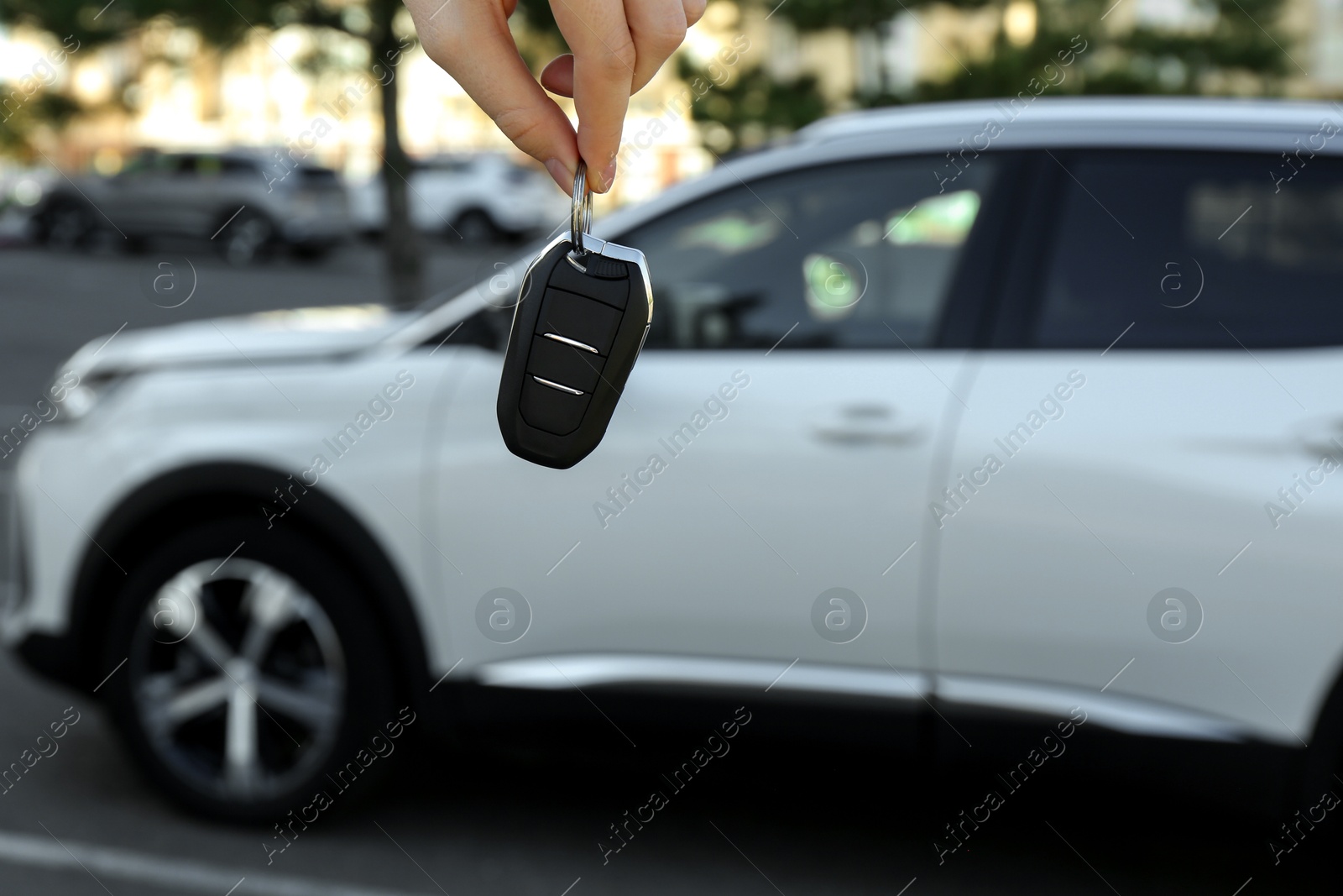 Photo of Woman holding key near car outdoors, closeup