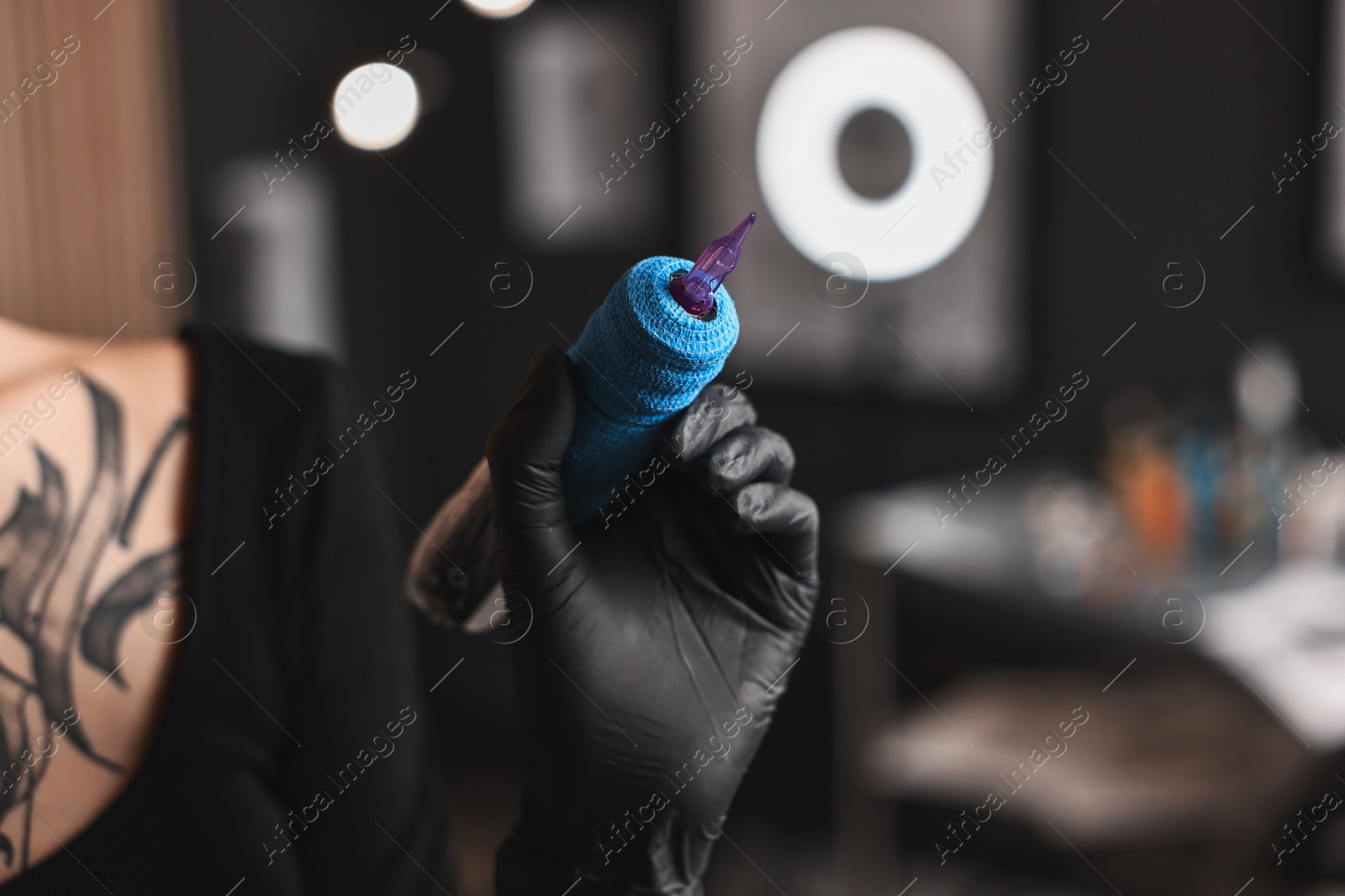 Photo of Professional artist in gloves with tattoo machine in salon, closeup. Space for text