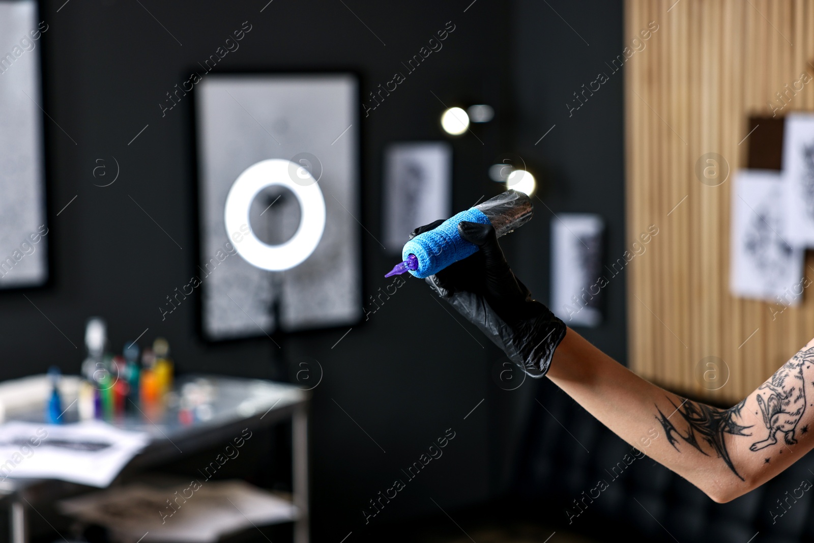 Photo of Professional artist in gloves with tattoo machine in salon, closeup. Space for text