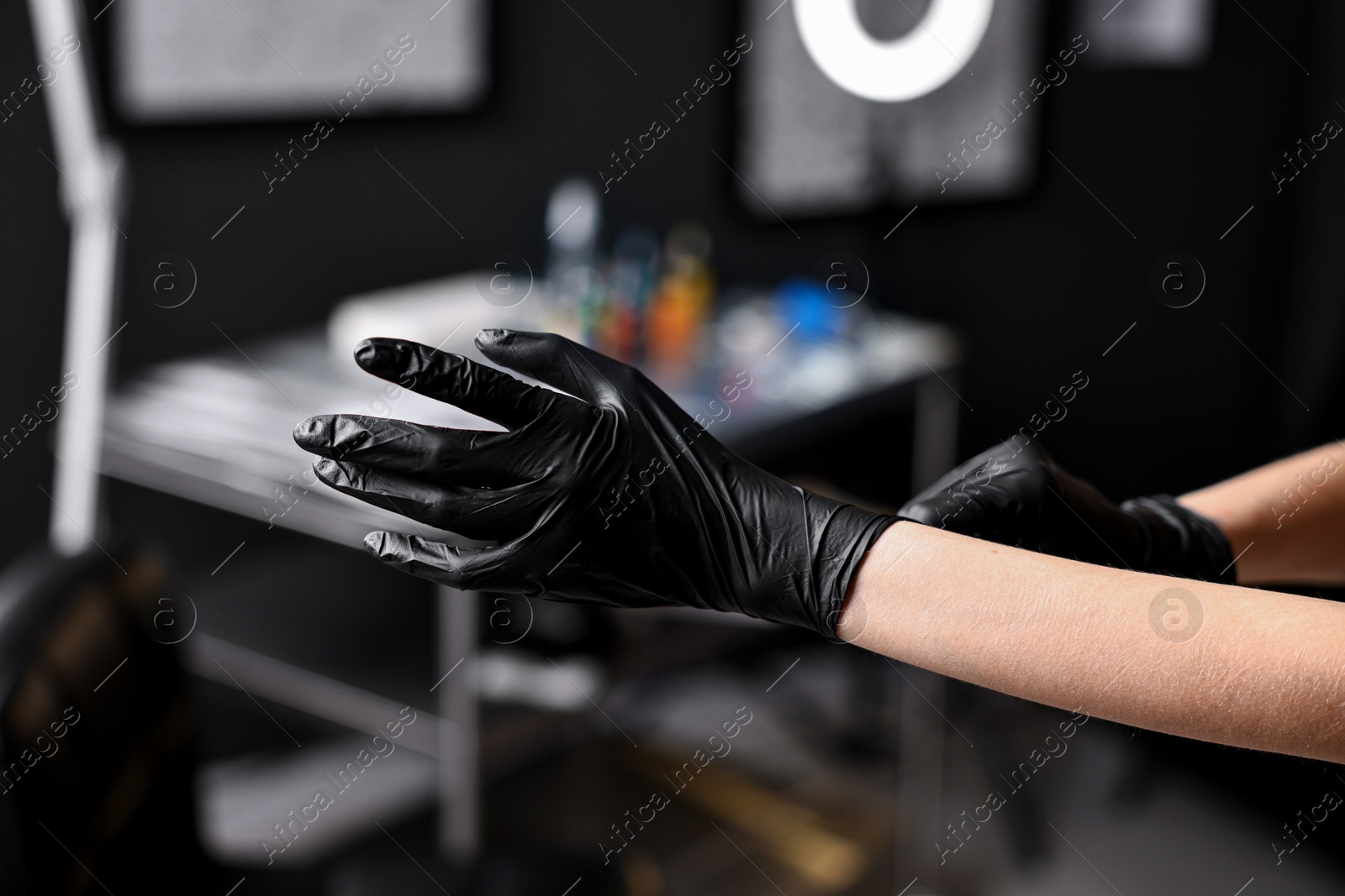 Photo of Professional tattoo artist wearing gloves in salon, closeup