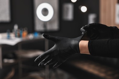 Photo of Professional tattoo artist wearing gloves in salon, closeup. Space for text