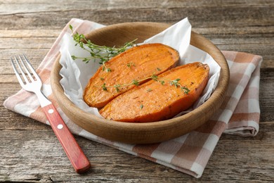 Photo of Tasty cooked sweet potato with thyme on wooden table, closeup