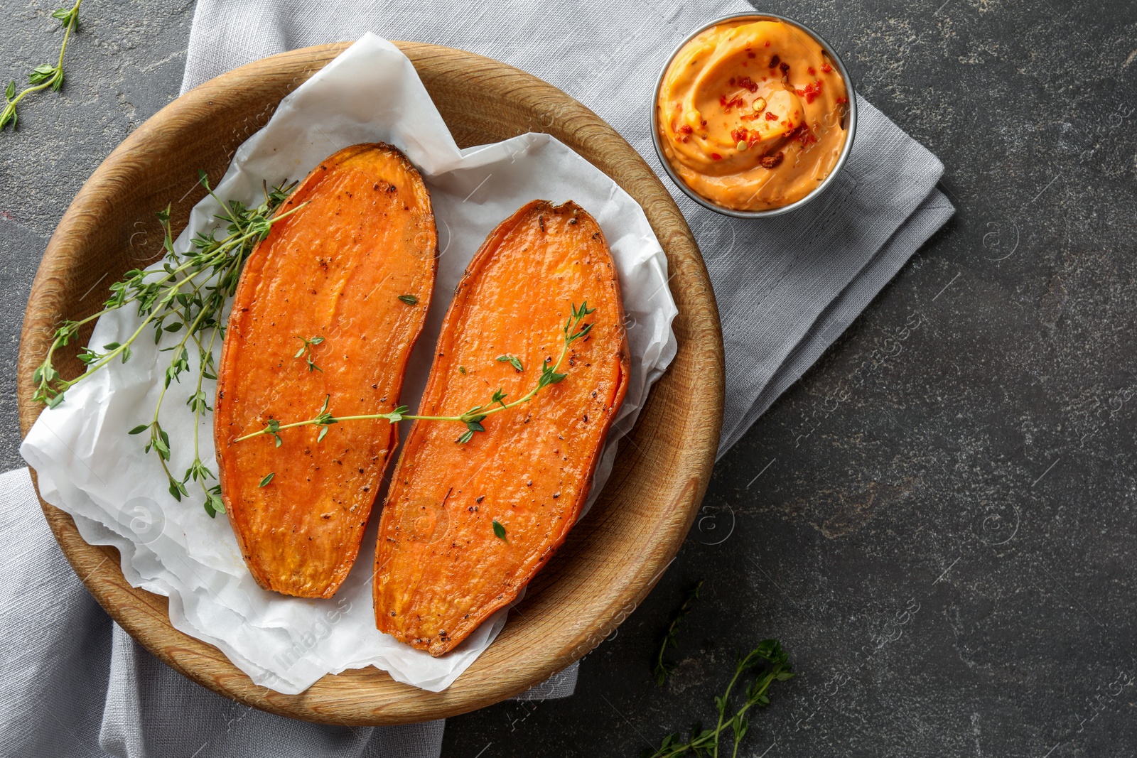 Photo of Tasty cooked sweet potato with thyme and sauce on grey table, top view