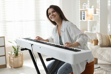 Photo of Smiling woman playing synthesizer at home. Electronic musical instrument