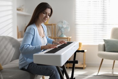 Photo of Beautiful woman playing synthesizer at home, space for text