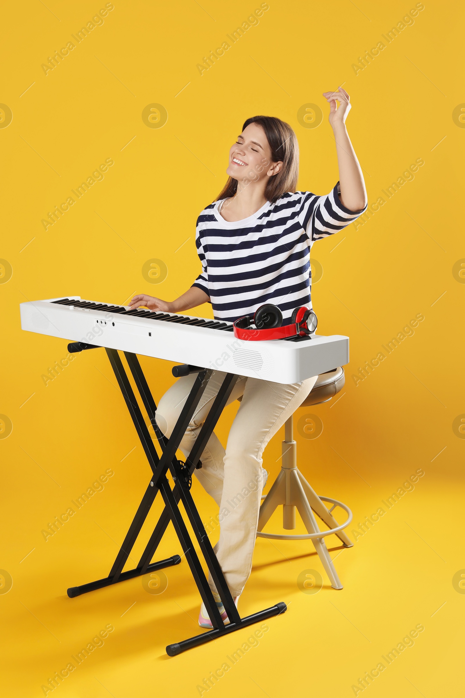 Photo of Smiling woman playing synthesizer on orange background