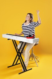 Photo of Smiling woman playing synthesizer on orange background