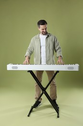 Photo of Bearded man playing synthesizer on olive background